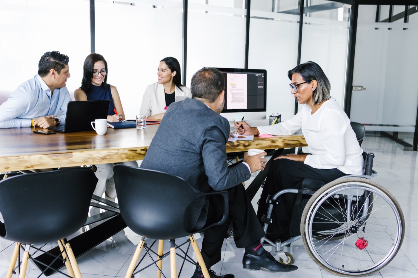 Colleagues in discussion around a conference table, one using a wheelchair