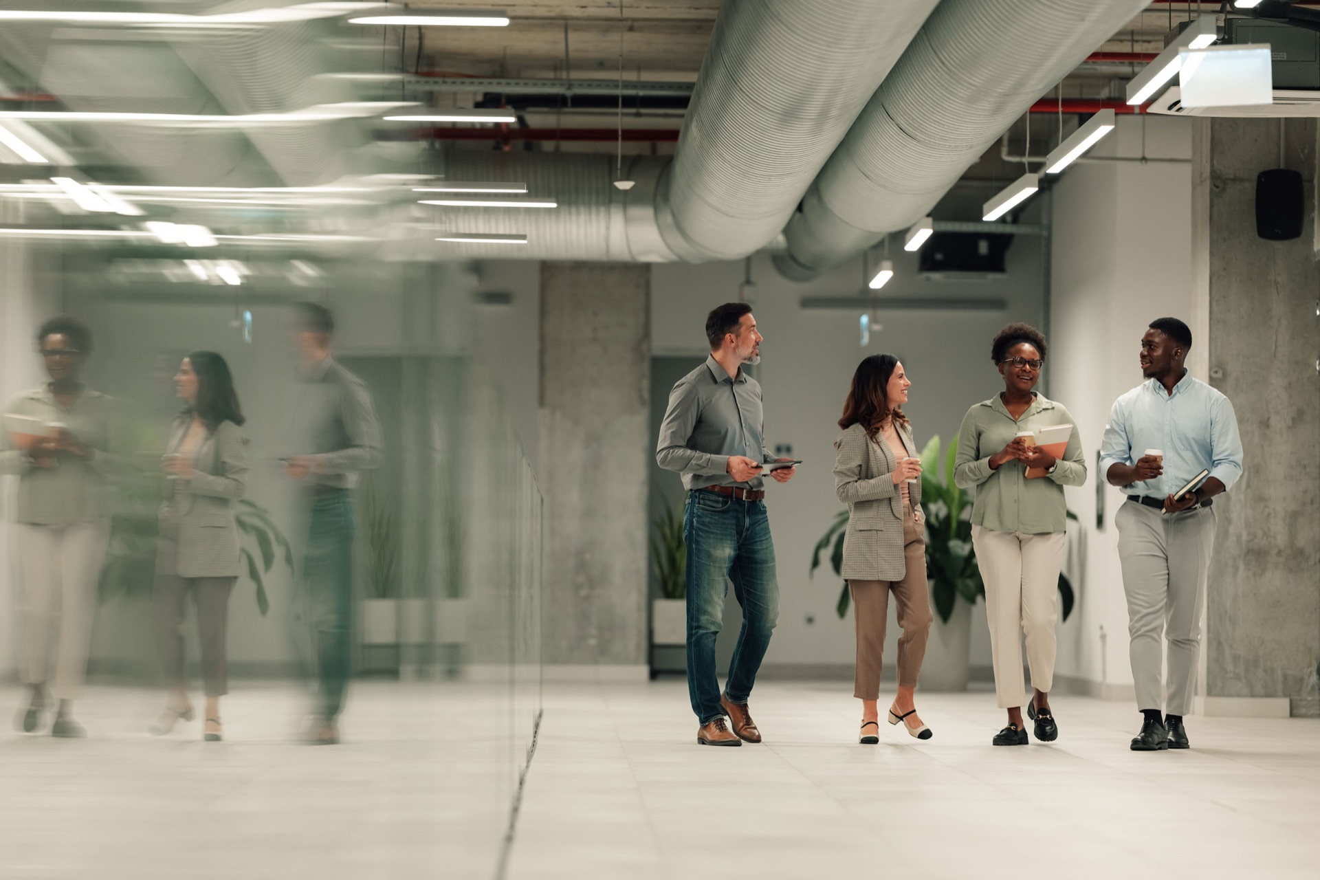 Four colleagues walking and talking in a modern office